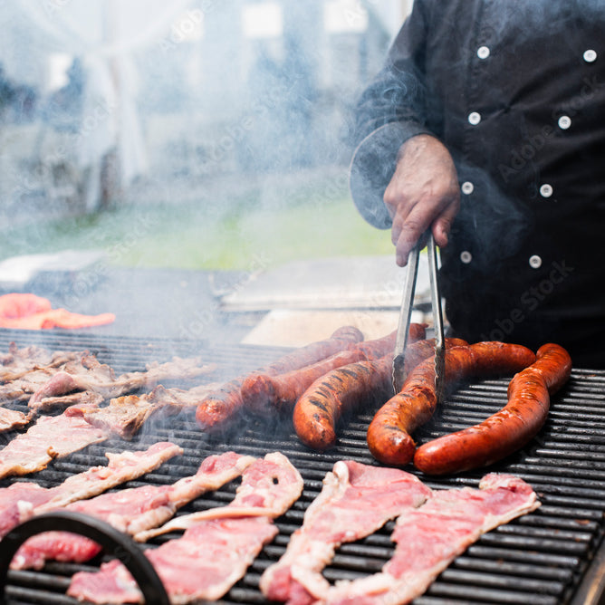 Man cutting slices into a smoked brisket. Actively cooking over a smoker. Blog image for Outdoor Living Australia