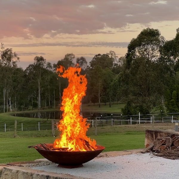Mega cauldron 1500 mm with raging fire inside in a backyard