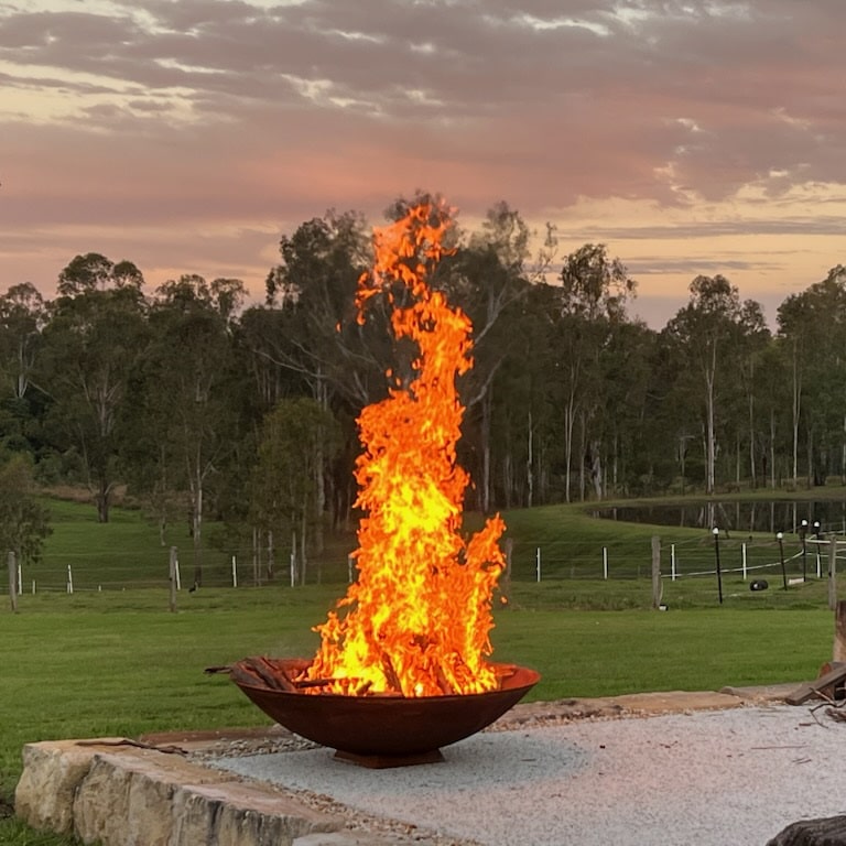 Mega cauldron 1500 mm with raging fire inside in a farm setting