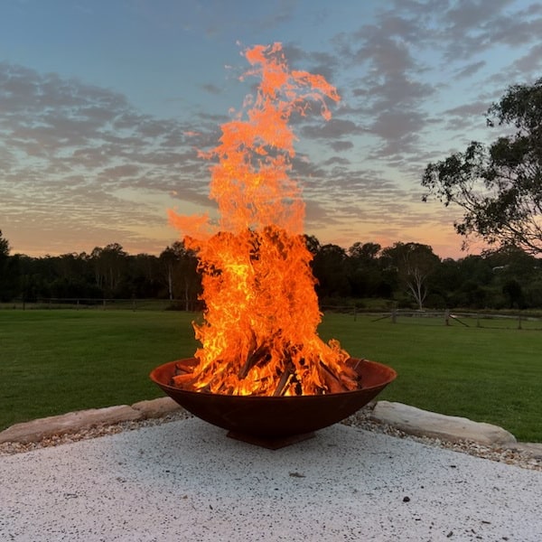 Mega cauldron 1500 mm with raging fire inside in an outdoor setting